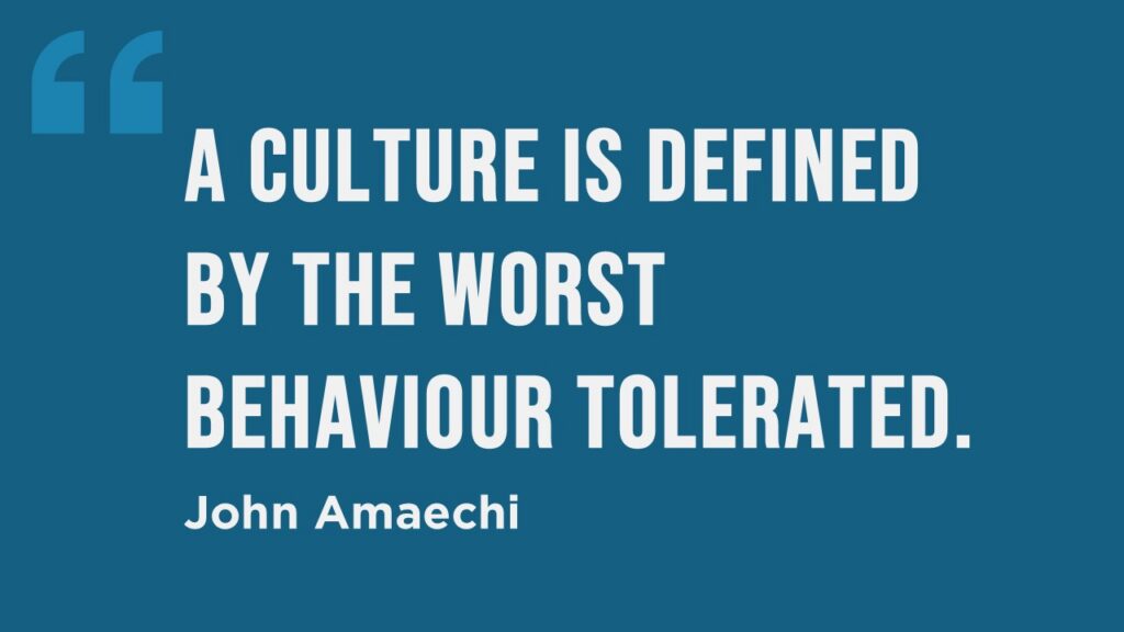 Quote on a blue background: 'A culture is defined by the worst behaviour tolerated.' – John Amaechi. The text is bold and white, with large quotation marks in the top left corner.